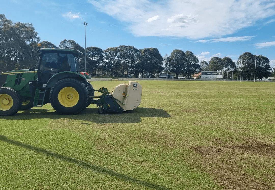 John Deere tractor with turf maintenance equipment on a large grounds site
